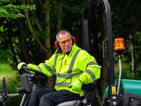 landscape contractor in hi-vis riding a Ransomes mower